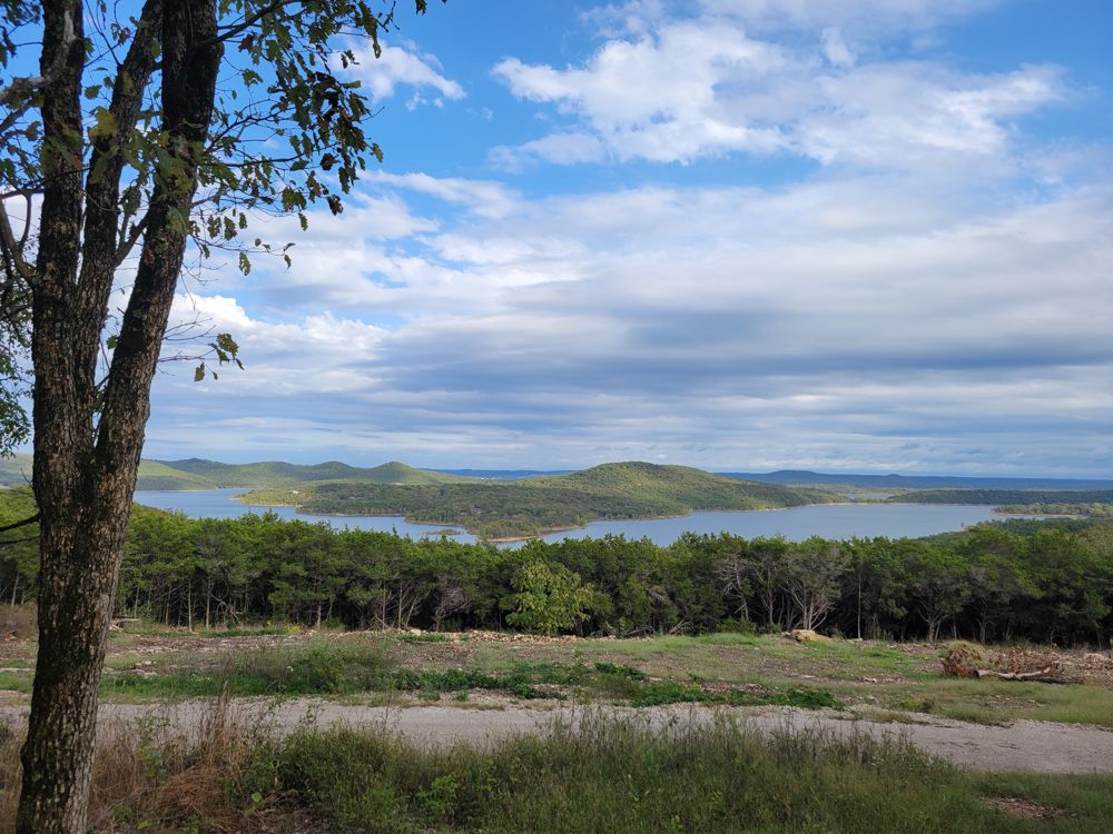 Wide view of Table Rock Lake and rolling, tree-covered Ozark hills under a partly cloudy sky.
