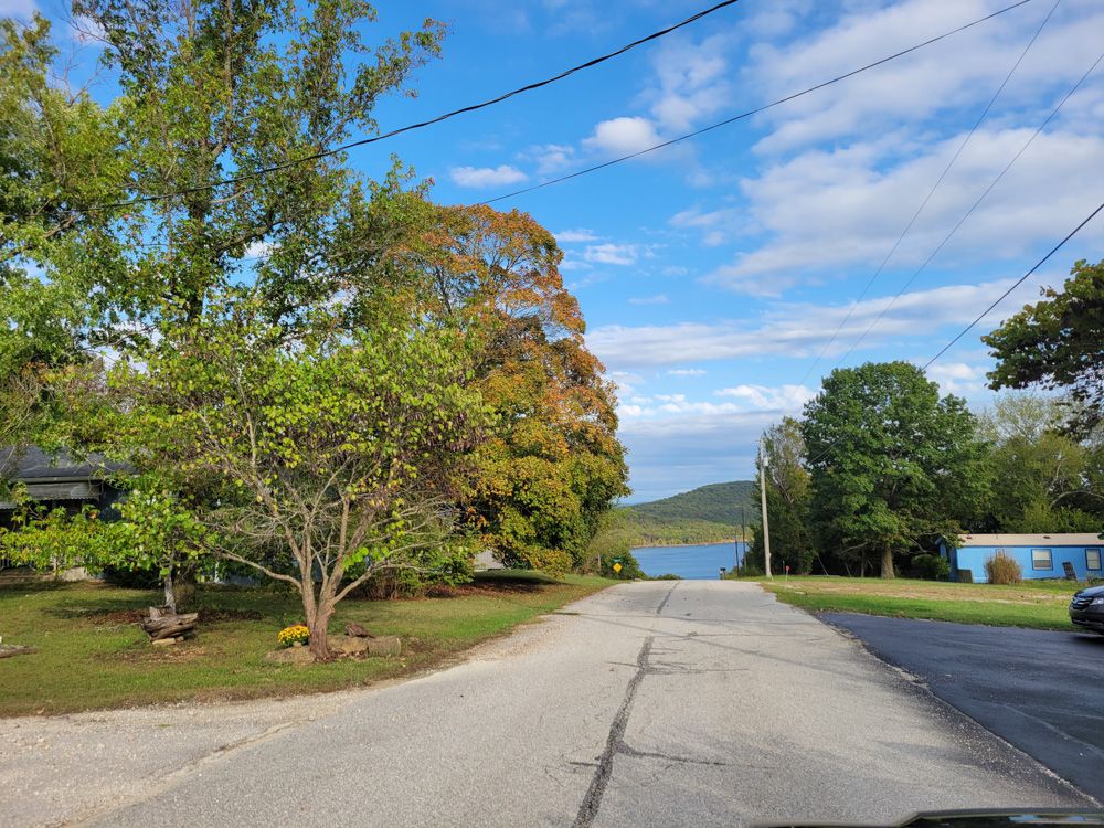 A quiet street near the park sloping down toward Table Rock Lake, lined with early-autumn trees.