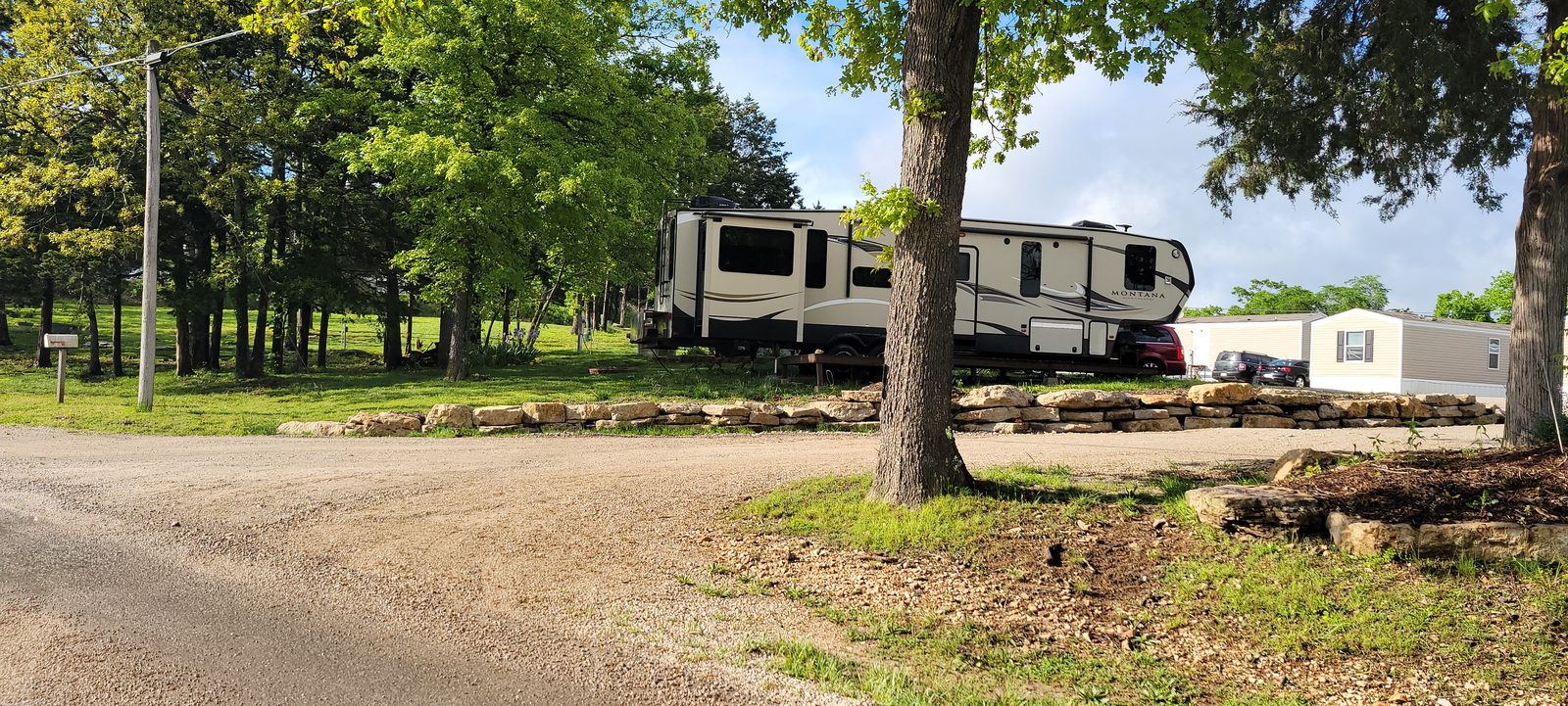 A Montana fifth-wheel set up on a spacious lakeside site.